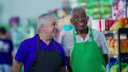 Photo for Happy diverse senior employees celebrating success with high-five standing in supermarket aisle. Caucasian manager engaging with workforce teamwork with African American colleague - Royalty Free Image