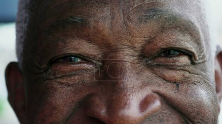 Foto de Un anciano negro cerrando los ojos en contemplación, macro primer plano de un anciano afroamericano meditando, abriendo los ojos mirando a la cámara sonriendo - Imagen libre de derechos