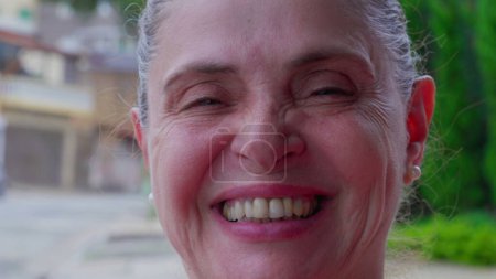 Foto de Mujer madura agrietando una sonrisa sintiendo felicidad de pie afuera en la calle de la ciudad. 50 mujer caucásica persona espontánea sonrisa - Imagen libre de derechos