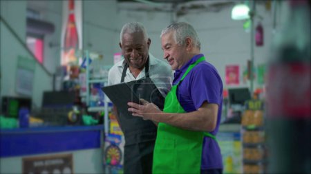 Foto de Empleados de Supermercado Senior con Dispositivo Tablet, Escena de Trabajo en Equipo del Gerente Mayor Instruyendo a sus Colegas - Imagen libre de derechos