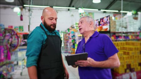 Photo for Senior manager of supermarket reproving employee, business boss reprimanding staff at grocery store holding tablet, showing lack of inventory - Royalty Free Image