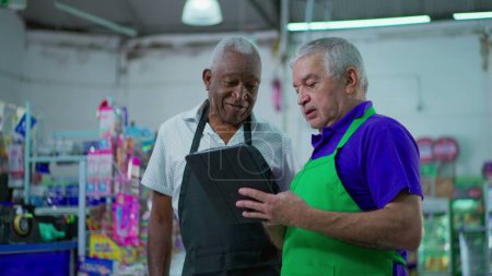 Photo for Two happy diverse senior staff of frocery store checking inventory operations with tablet device, older employees of supermarket laughing and smiling at workplace - Royalty Free Image