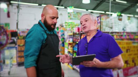Photo for Senior manager of supermarket reproving employee, business boss reprimanding staff at grocery store holding tablet, showing lack of inventory - Royalty Free Image
