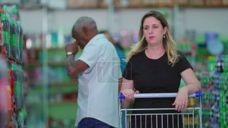 Foto de Compradores de compras en el supermercado depicing hábitos de estilo de vida de consumismo. Grupo de buceadores de personas caminando en el pasillo de la tienda de comestibles - Imagen libre de derechos