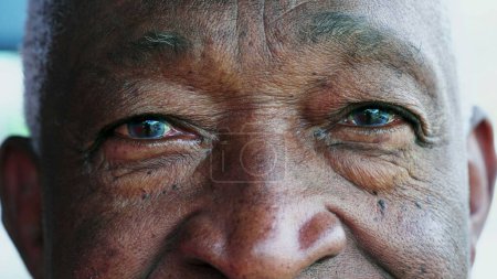 Foto de Macro apretado primer plano de un hombre mayor afroamericano con ojos azules mirando a la cámara. Cara de retrato de un hombre mayor negro con arrugas que representan la vejez y la sabiduría - Imagen libre de derechos