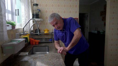 Photo for Stressed senior man leaning on kitchen sink struggling in despair at home, older person suffering breakdown crisis alone in solitude, depression and anxiety concept in old age - Royalty Free Image