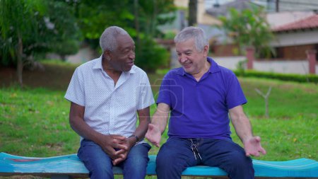 Foto de Dos personas mayores hablando y riendo sentadas en el banco del parque en Brasil. Auténticas personas sinceras la vida real risa y sonrisa en la vejez jubilación años dorados - Imagen libre de derechos