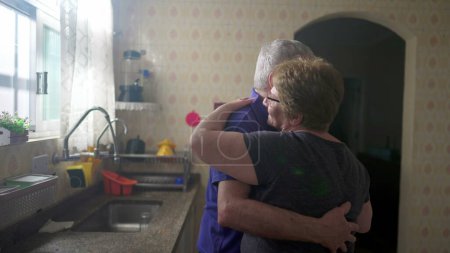 Photo for Romantic Scene of Elderly Couple Dancing by Kitchen Window, Senior Husband and Wife in Loving Embrace - Royalty Free Image