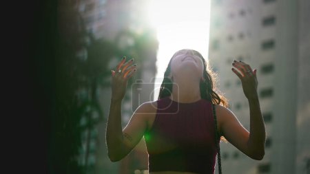 Photo for One Spiritual young woman standing outdoors looking up at sky feeling hopeful. Faithful person feeling the presence of God in nature sunlight - Royalty Free Image