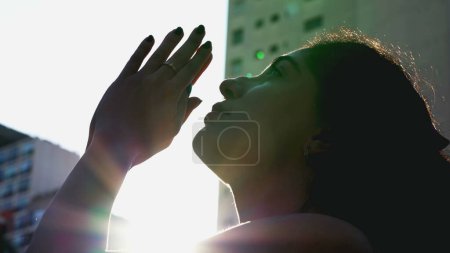 Téléchargez les photos : Une jeune femme paisible priant dehors sous la lumière du soleil. Personne spirituelle en prière avec une fusée éclairante. Émotion méditative consciente - en image libre de droit