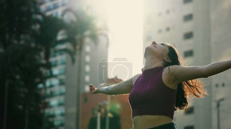 Photo for Carefree happy woman arms raised outside looking at sky feeling grateful. Person celebrating life standing in nature sunlight - Royalty Free Image