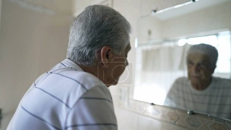 Photo for Caucasian Senior Man Reflecting on Regret and Sorrow, Contemplating Old Age in Bathroom Mirror - Royalty Free Image