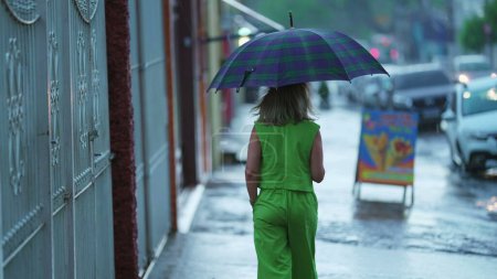 Téléchargez les photos : Vue arrière de la personne marchant sous la pluie tenant parapluie - en image libre de droit