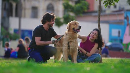 Téléchargez les photos : Couple heureux avec Golden Retriever chien animal de compagnie au parc de la ville pendant une belle journée ensoleillée - en image libre de droit