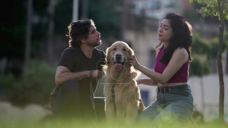 Téléchargez les photos : Couples sincères profitant de la journée d'été au parc avec leur Golden Retriever Pet au soleil - en image libre de droit