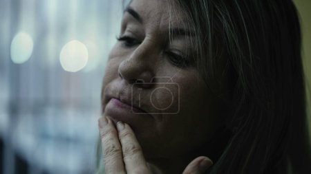 Photo for Mature woman with worried emotion, close-up face looking down in sorrow and grief. 50s person in melancholy - Royalty Free Image