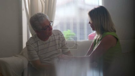 Photo for Senior man struggling with difficulties being being listened by supportive female partner during hard times. Woman active listening an elderly person at home seated in candid scene - Royalty Free Image