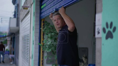 Foto de Hombre abriendo la tienda de la ciudad Garaje para iniciar el día de negocios - Imagen libre de derechos