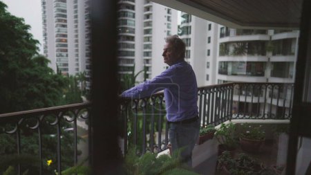 Photo for One pensive senior man standing at apartment balcony looking out. Contemplative male 70s person thinking about life - Royalty Free Image