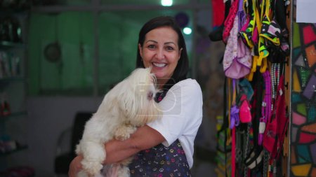 Foto de Propietario de la tienda Happy Pet. Sonriendo, sosteniendo perro pequeño, retrato de empleada en delantal con Shih-Tzu - Imagen libre de derechos