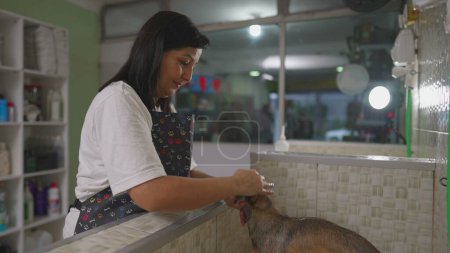 Foto de Mujer empleada aplicando champú a pequeño perro dentro de la tienda de mascotas - Imagen libre de derechos