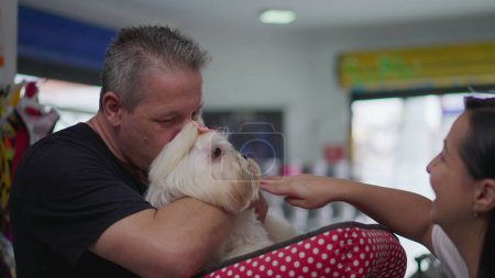 Photo for Happy Pet Client Holding Small Dog. Female Business Owner Handing Shih-Tzu to Man after Grooming Bath - Royalty Free Image