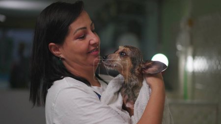 Foto de Retrato de una mujer feliz secando Perro pequeño con toalla dentro de Pet Shop. Mujer Pequeña Empresa propietaria de tienda local de mascotas seca compañero canino - Imagen libre de derechos