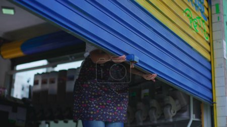 Foto de Persona cerrando garaje local. Mujer deslizándose por la fachada de negocios - Imagen libre de derechos