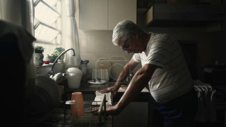 Photo for Struggling Senior man leaning on kitchen counter suffering from difficultires and preoccupation lifting head to window feeling angst - Royalty Free Image