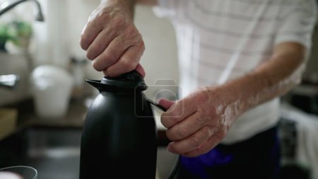 Téléchargez les photos : Gros plan main serrage et desserrage thermos bouteille préparant boisson chaude, café ou thé - en image libre de droit