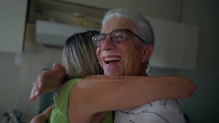 Foto de Amigo mayor feliz reunión. Mujer de mediana edad abrazando a un hombre mayor en la cocina. Gente abrazo auténtico - Imagen libre de derechos
