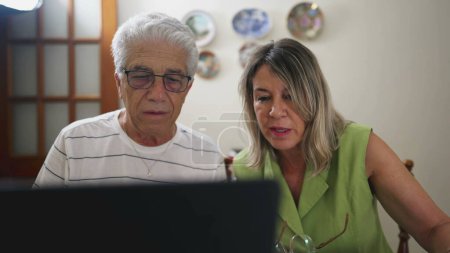Téléchargez les photos : Couple âgé en détresse, Discuter des problèmes financiers à la maison devant un ordinateur portable. Mari et femme bouleversés se disputant sur l'amende de la voiture, payer la dette - en image libre de droit