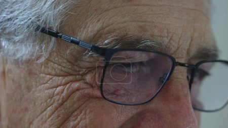 Photo for Elderly man close-up eyes with reading glasses. Senior person detail face with wrinkles depicting old age, typing on keyboard off-camera - Royalty Free Image