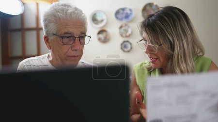 Téléchargez les photos : Couple âgé stressé examinant les finances, étudiant le document dans la cuisine de la maison - en image libre de droit