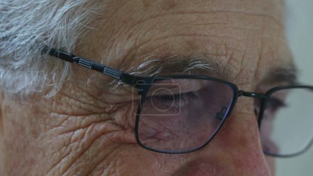 Téléchargez les photos : Homme âgé yeux rapprochés avec des lunettes de lecture. Visage de détail de la personne âgée avec rides représentant la vieillesse, tapant sur le clavier hors caméra - en image libre de droit
