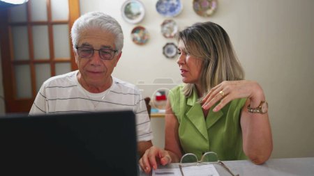 Téléchargez les photos : Couple de personnes âgées en difficulté faisant face à des problèmes financiers devant un ordinateur portable dans la cuisine - en image libre de droit