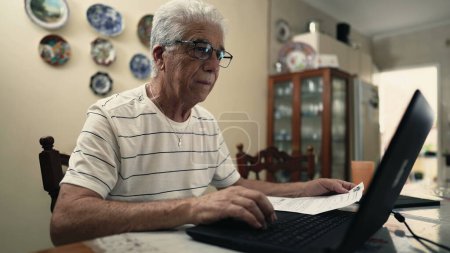 Photo for Senior Citizen Concerned Over Fine Debt Paper Beside Laptop, troubled retired man using computer to pay due bill - Royalty Free Image