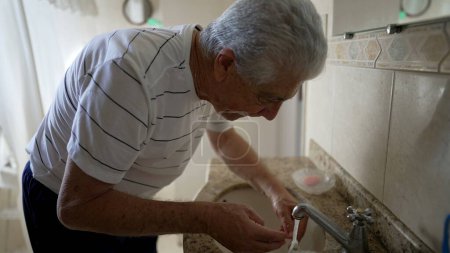 Foto de Escena doméstica casual del anciano cepillándose los dientes como parte de la rutina matutina. persona mayor higiene dental y lavado de la cara, comenzando el ritual del día - Imagen libre de derechos