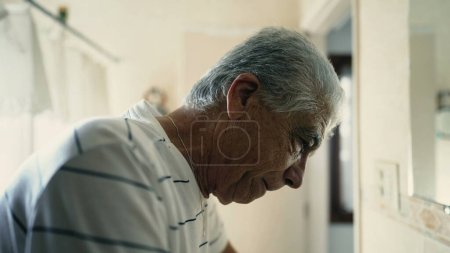 Photo for Dramatic senior elderly man standing in bathroom staring at mirror reflection experiencing old age - Royalty Free Image