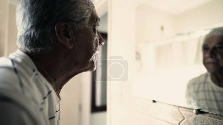 Foto de Hombre mayor mirando reflejo del espejo del baño. Anciano canoso mirándose a sí mismo - Imagen libre de derechos