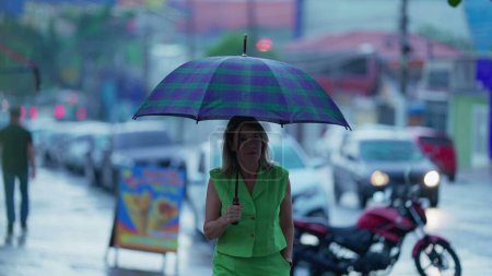 Téléchargez les photos : Femme marchant sous parapluie, se promenant pendant la journée pluvieuse en milieu urbain. Parapluie tenant une personne, Avancer dans la ville pluvieuse, Protection contre les intempéries - en image libre de droit