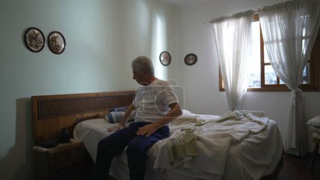 Photo for Senior man sitting on bedside, authentic real life portrait of elderly gray-hair person in casual bedroom, lifestyle scene depicting old age retirement - Royalty Free Image