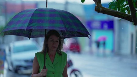 Foto de Mujer caminando bajo paraguas, paseando durante el día lluvioso en un entorno urbano. Paraguas de retención de personas, Caminando hacia adelante en Rainy City, Protección contra el mal tiempo - Imagen libre de derechos