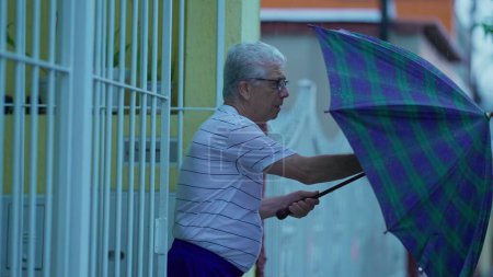 Téléchargez les photos : Homme âgé arrivant à la maison pendant la journée de pluie, tenant un parapluie et ouvrant la porte. Une personne âgée marche tous les jours pendant la pluie, clip au ralenti - en image libre de droit