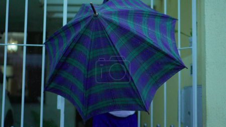 Téléchargez les photos : Homme âgé ouvrant parapluie à l'abri de la pluie, sort dans la rue de la maison. Personne âgée quittant la résidence, ouvre des promenades sur le trottoir urbain sous la pluie - en image libre de droit