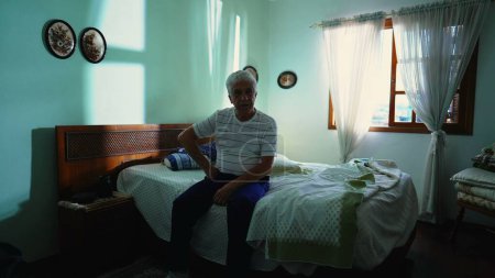 Téléchargez les photos : Homme âgé aux cheveux gris dans une chambre décontractée, portrait sombre de la retraite dans la vieillesse, dépeignant la solitude et la solitude - en image libre de droit