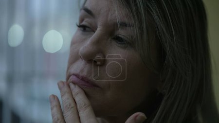 Photo for Pensive middle-aged woman close-up face with ruminating introspective thoughts. Preoccupied person in 50s in contemplation, pondering decision-making - Royalty Free Image