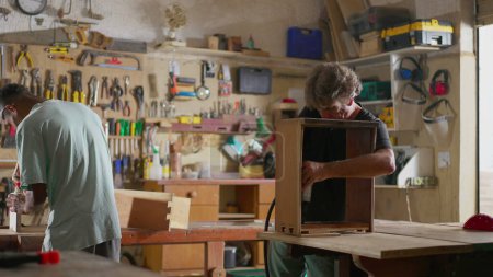 Téléchargez les photos : Scène de menuiserie de deux menuisiers travaillant avec des outils pour construire et réparer des meubles en bois - en image libre de droit