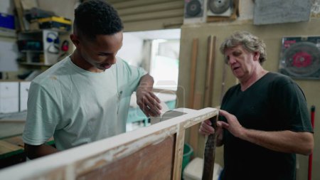 Téléchargez les photos : Menuisiers travaillant à l'atelier. Senior et jeune employé polissage de meubles en bois, authentique petite entreprise brésilienne en Amérique du Sud - en image libre de droit