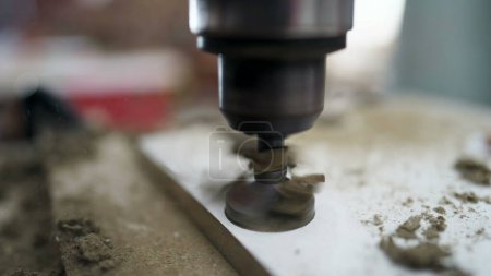 Foto de Detalle de una máquina de perforación de alta velocidad que hace un agujero en una superficie de madera, equipo industrial - Imagen libre de derechos